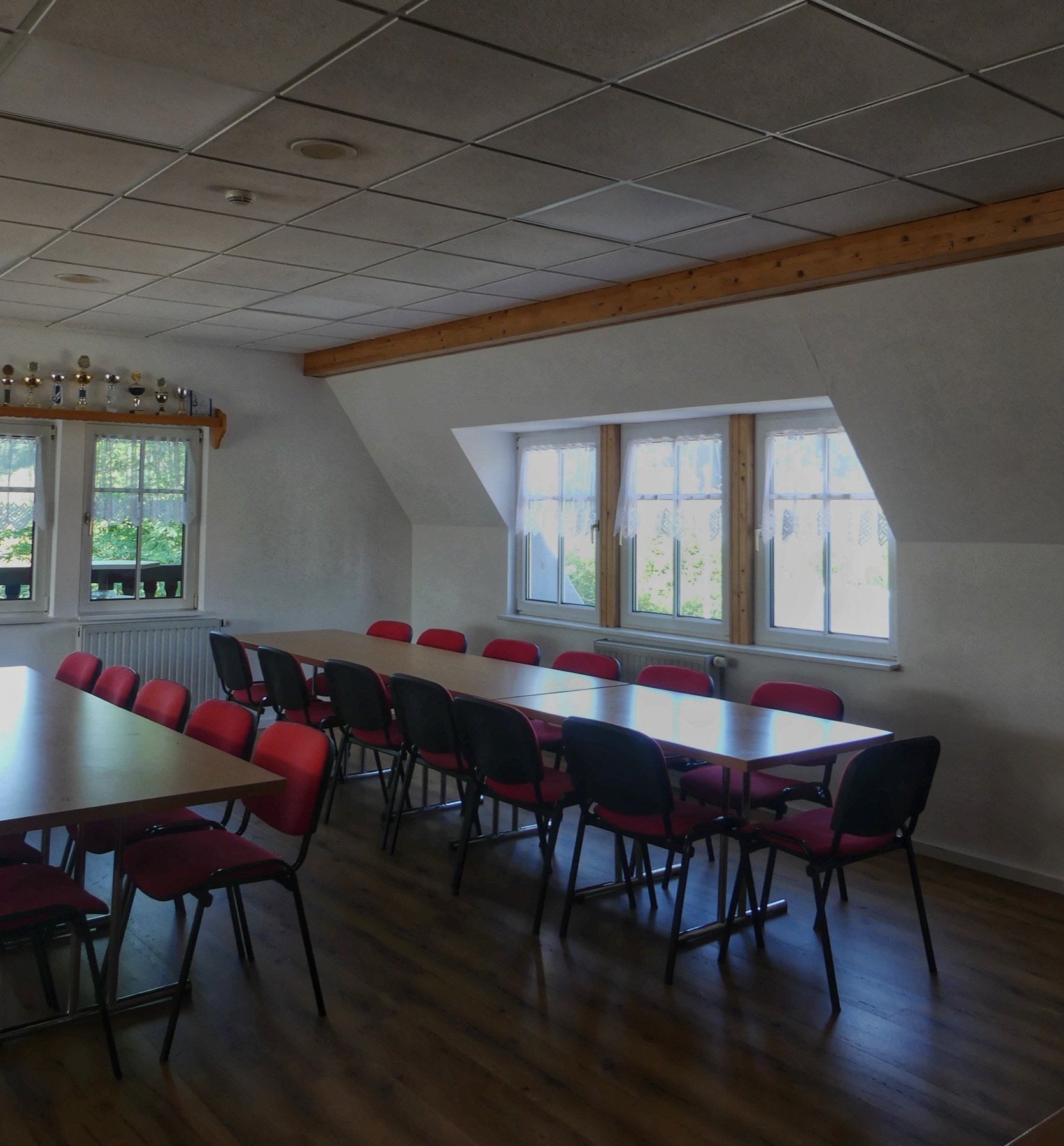 Clubraum mit Tischen, Stühlen und Pokalvitrine